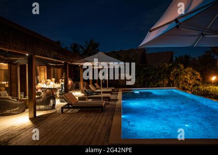 Die Gäste genießen das Abendessen am privaten Swimmingpool einer Residence Villa im Six Senses Fiji Resort bei Nacht, Malolo Island, Mamanuca Gro Stockfoto