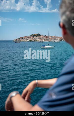 Segelboote vertäuten im Hafen mit der Altstadt in der Ferne und verschwommen Menschen im Vordergrund, Primosten, Šibenik-Knin, Kroatien, Europa Stockfoto