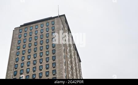 Regelmäßige rechteckige Fenster auf Wohnblocks/Bürogebäuden. Hintergrund des bewölkten Himmels Stockfoto