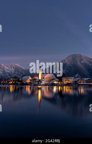 Blick über den winterlichen Tegernsee auf das Dorf Rottach-Egern mit der Kirche Sankt Laurentius, Bayern, Deutschland. Stockfoto