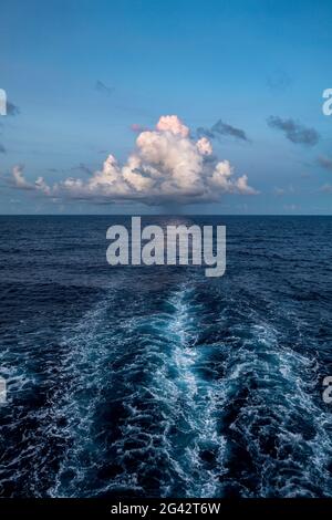 Wellen hinter dem Passagierfrachtschiff Aranui 5 (Aranui Cruises) mit einer majestätischen Wolke am Horizont, auf See zwischen den Marquesas-Inseln und den Tuamotu Stockfoto