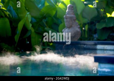 Morgengrauen auf der Oberfläche eines Pools mit einer Hindu-Statue an der Seite. Gedreht in einer typischen Umgebung. Bali, Indonesien Stockfoto