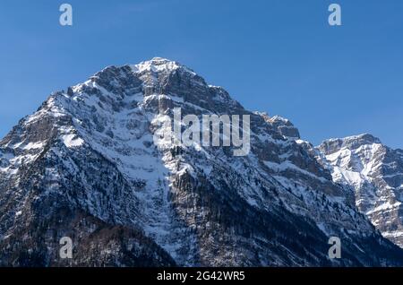 Ein steiles und schroffes Mozntain-Gesicht, das unter Schnee liegt Ein blauer Himmel in den Schweizer Alpen Stockfoto