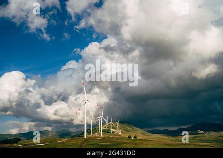 Viele Windturbinen auf dem Hügel, vor der Kulisse eines epischen Himmels. Stockfoto