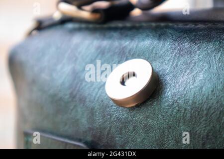 Nahaufnahme von Gold magnetische Knopfverschluss öffnen elegante Damen Mode grünen Leder Umhängetasche. Zubehör, Detail Stockfoto