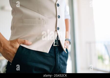 Ein Mann hält seine Hände in den Hosentaschen Ein Hotelzimmer während der Vorbereitung auf eine Hochzeitszeremonie Stockfoto