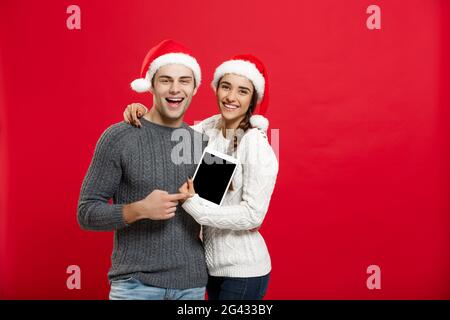 Weihnachten Konzept - glückliches junges Paar in Weihnachten Pullover Holding digital Tablet Stockfoto
