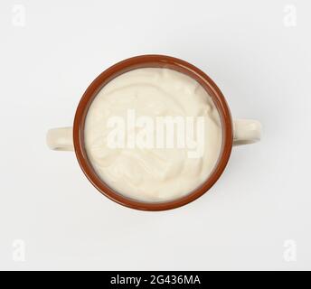 Saure Rahm in einer braunen Keramikschale auf weißem Hintergrund, fermentiertes Milchprodukt Stockfoto