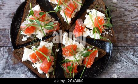 Keto-Diät. Keto-Snack. Teller mit Toast mit Lachs und Weißkäse. Stockfoto