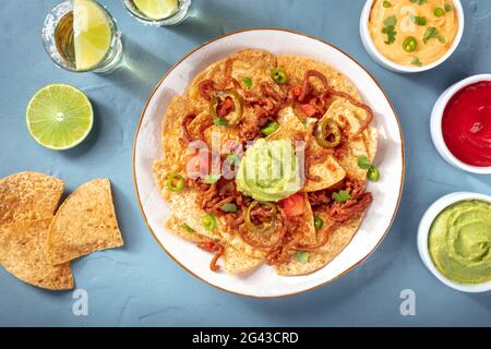 Mexikanische Nachos, von oben mit einer Vielzahl von Dips und Saucen geschossen Stockfoto