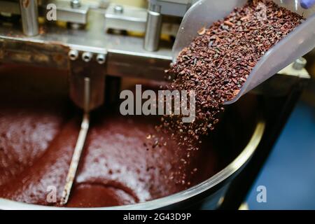 Handwerkliche Schokoladenherstellung, Zugabe von Kakaomühlen in der Melanger Steinmühle. Stockfoto