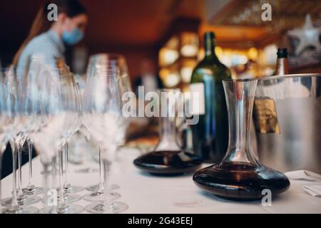 Der Kellner gießt erlesenen Rotwein in die Dekanter auf dem Tisch im Restaurant Stockfoto