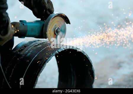 Der Winkelschleifer schneidet ein Metallrohr mit großem Durchmesser und Funken fliegen. Nahaufnahme der Arbeit in der Produktion. Stockfoto