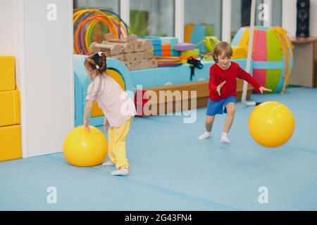Kinder machen Übungen mit Big Ball im Fitnessstudio im Kindergarten oder in der Grundschule. Sport- und Fitnesskonzept für Kinder. Stockfoto