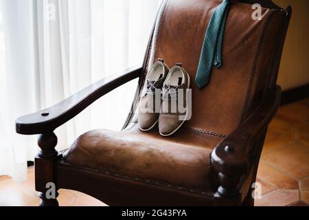 Sessel aus echtem Leder in einem Raum mit Herrenschuhen und Krawatte. Stockfoto