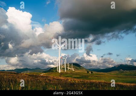 Windturbinen im Feld vor dem Hintergrund eines epischen Himmels. Stockfoto