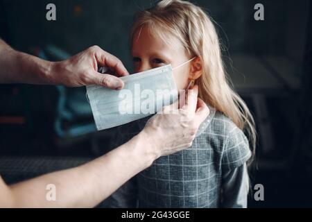 Eltern helfen Tochter Dressing Uniform und legen Gesichtsmaske Vorbereitung Zurück zur Schule Stockfoto