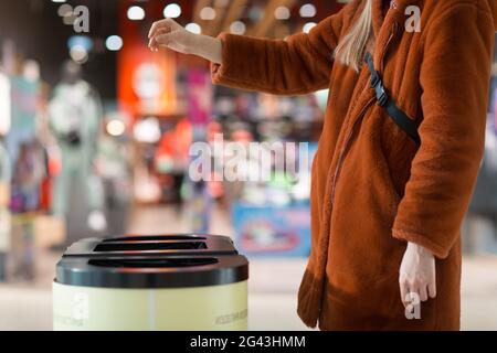 Frau wirft Gegenstand in den Papierkorb. Vorlage mit leerem Leerzeichen Stockfoto