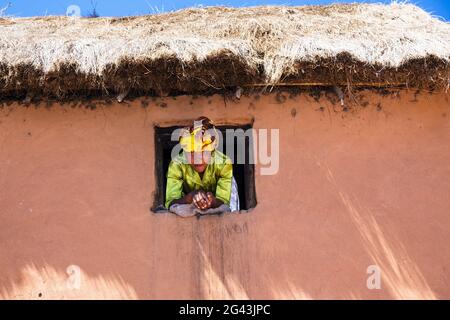 Frau schaut aus dem Fenster, Dorf im Hochland von Madagaskar, Afrika Stockfoto