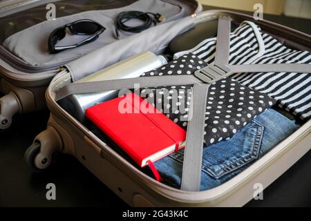 Offener Koffer voller Kleidung auf schwarzem Hintergrund isoliert Stockfoto
