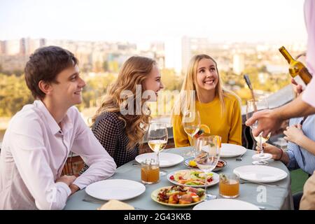 Fröhliche Freunde trinken während der Dachparty Weißwein Stockfoto