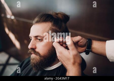 Barbershop mit Interieur aus Holz. Bärtige Modell Mann und Friseur. Stockfoto