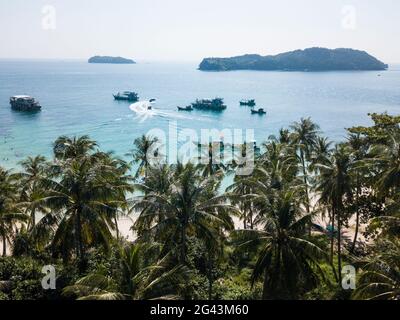 Luftaufnahme von Kokospalmen in Strandnähe mit Ausflugsbooten, Fischerbooten und Inseln in der Ferne, May Rut Island, in der Nähe von Phu Quoc Island, Kien Gi Stockfoto