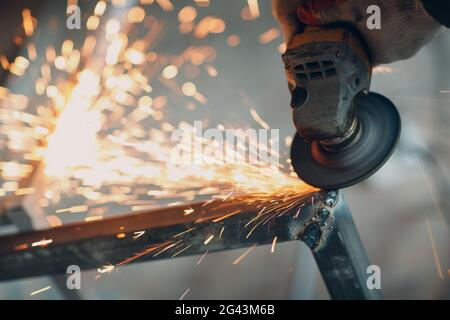 Handwerker Sägen von Metall mit dem Winkelschleifer sah in der Werkstatt Stockfoto
