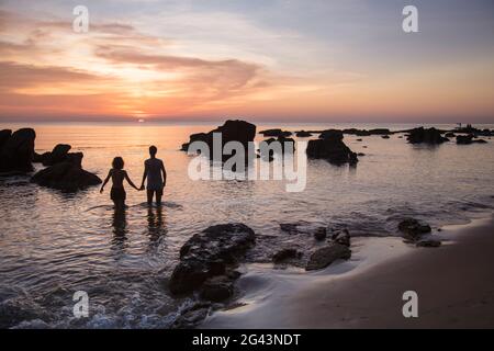 Silhouette eines jungen Paares, das bei Sonnenuntergang am Ong lang Beach, Ong lang, Phu Quoc Island, Kien Giang, Vietnam, Asien Stockfoto