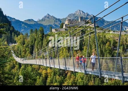 Mehrere Menschen laufen über die Seilbrücke Highline 179 mit der Burgruine Ehrenberg im Hintergrund, Reutte, Tirol, Österreich Stockfoto