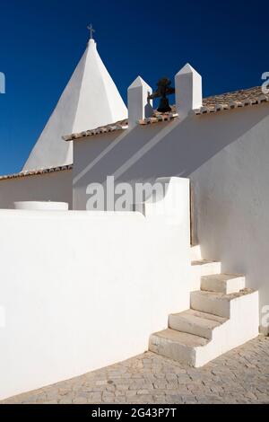 Ein weißes Kapellengebäude an der Algarve in Portugal. Architekturaufnahme mit Fokus auf Spahes, Schatten und Formen. Stockfoto