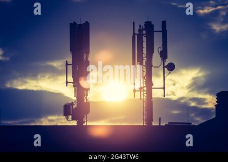 5g und Kommunikationsturm: Silhouette des Kommunikationsturms auf dem Dach, Abend Stockfoto