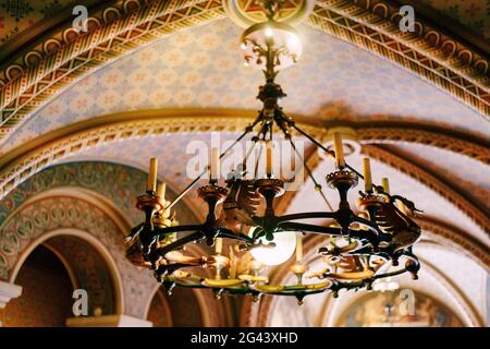 Mittelalterlicher Kronleuchter mit Wachskerzen. Kronleuchter aus Metall im Schlossstil mit echten Kerzen. Stockfoto