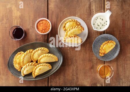 Empanadas mit Saucen und Wein, Schuß von der Oberseite in einem dunklen Holzmöbeln im Landhausstil Hintergrund Stockfoto