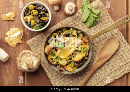 Ein Foto von einem rustikalen Pilz und Oliven, die mit Minze anbraten Stockfoto