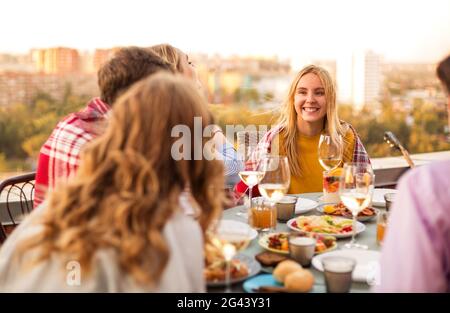 Fröhliche Freunde trinken während der Dachparty Weißwein Stockfoto