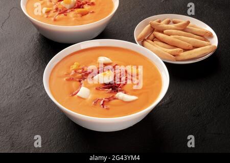 Salmorejo, spanische kalte Tomatensuppe, auf schwarzem Hintergrund mit picos Stockfoto