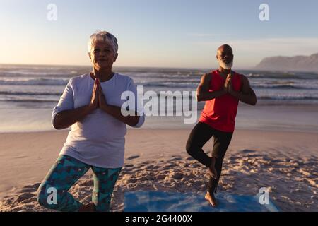 Senior african american Couple mit gefalteten Händen meditieren und üben Yoga gemeinsam am Strand Stockfoto