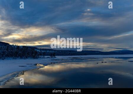 Winterstimmung mit glühenden Wolken an einem See in Lappland, Arjeplog, Schweden Stockfoto