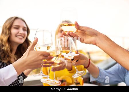 Fröhliche Freunde trinken während der Dachparty Weißwein Stockfoto