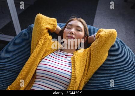 Geschäftsfrau mit gemischter Rasse, die im Büro chillt und sich entspannt in einem Raum herumliegt Sitzsack Stockfoto