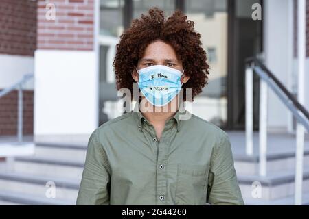 Porträt eines Mannes mit gemischter Rasse, der eine Gesichtsmaske trägt Schreiben Stockfoto