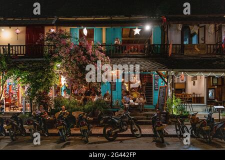 Mopeds stehen vor dem belebten Restaurant und der Bar an der Sisavangvong Road (der Hauptstraße), Luang Prabang, Luang Prabang Provinz, Laos, Asien Stockfoto