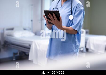 Mittelteil der kaukasischen Ärztin im Krankenhaus mit Peelings und Stethoskop mit Tablet Stockfoto