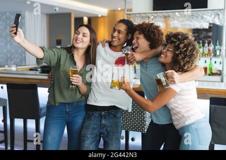 Verschiedene Gruppen von männlichen und weiblichen Geschlechts, die Brillen erheben und nehmen Selfie an der Bar Stockfoto