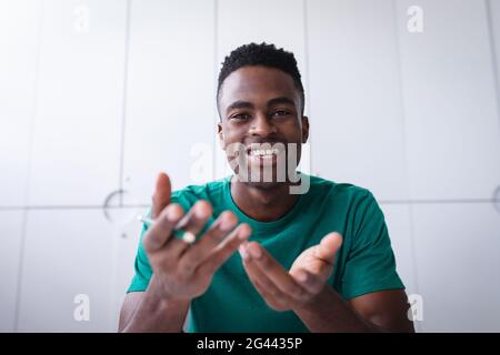 Glücklicher afrikanischer amerikanischer Geschäftsmann, der am Schreibtisch sitzt, während er einen Videoanruf Notizen machen Stockfoto