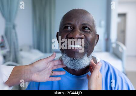 Kaukasische Ärztin, die Lymphknoten des afroamerikanischen Mannes tastend Patient Stockfoto