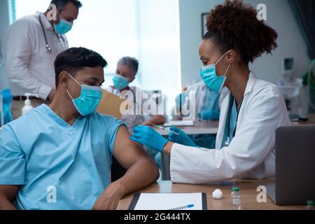 Gemischte Rasse paar Ärzte tragen Gesichtsmasken machen Injektion Stockfoto