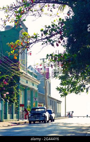 Blick auf die Straße mit bunten Gebäuden, Blumen und einem Oldtimer in Cienfuegos, Kuba Stockfoto