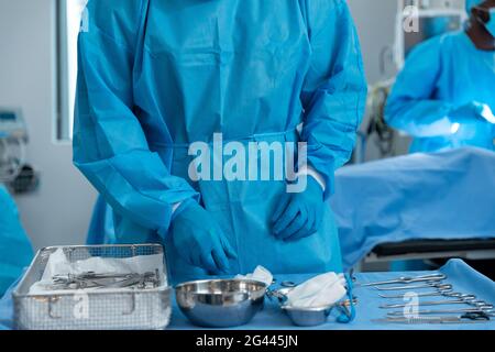 Mittelteil eines männlichen Chirurgen, der im Operationssaal Schutzkleidung trägt Stockfoto